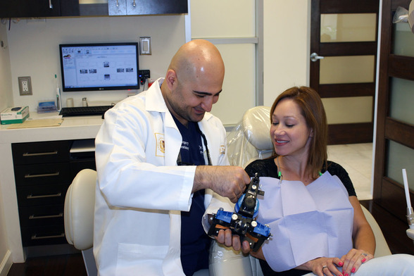 Dr, Samo holding a dental articulator with a patient. 